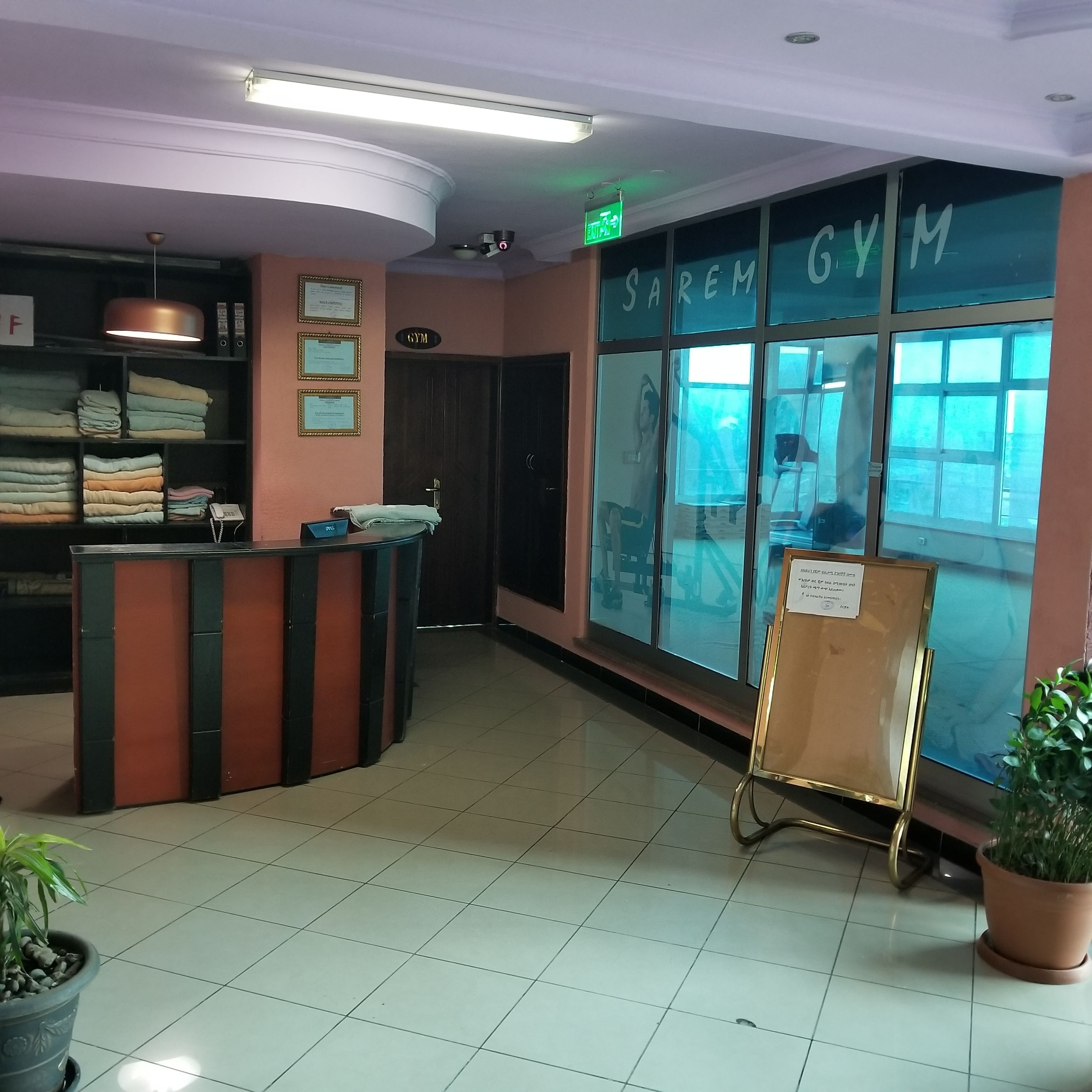 A reception area with a counter, a large window with a view, and a sign that reads "SAREM GYM".