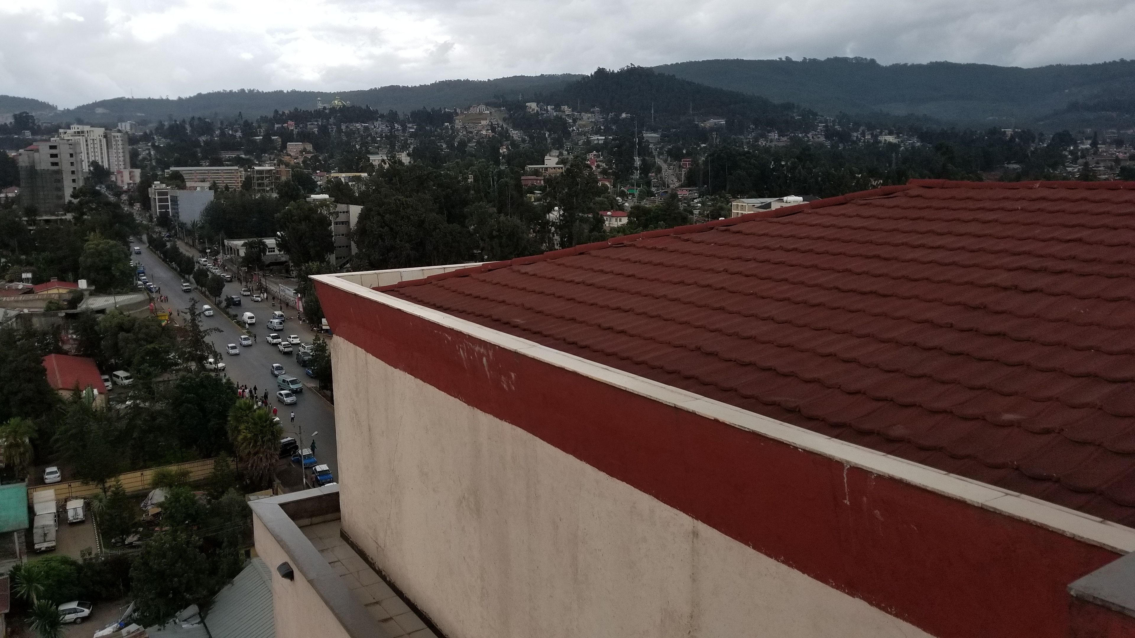 Um edifício alto com telhado vermelho, com vista para uma paisagem urbana com ruas e edifícios.