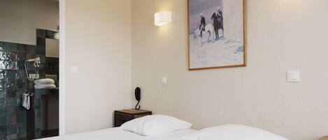 A hotel room with a bed, a nightstand, a telephone, and a poster on the wall.