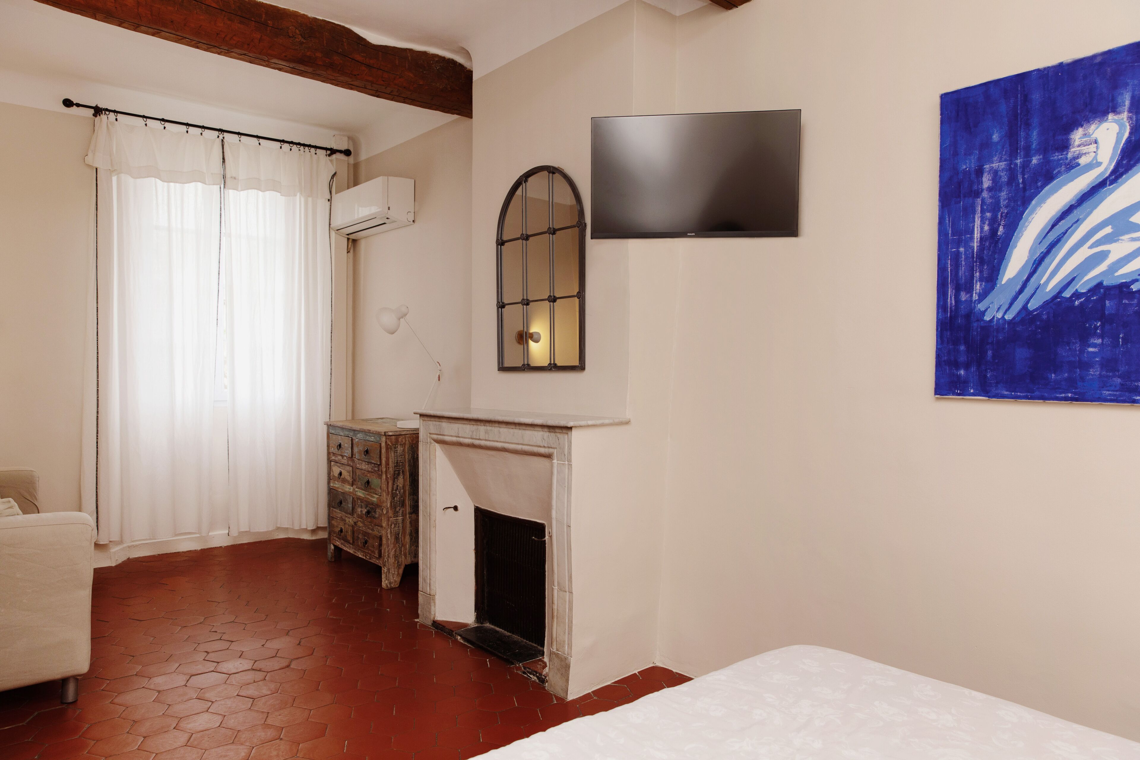 Un dormitorio con chimenea, televisor montado en la pared y un cuadro.