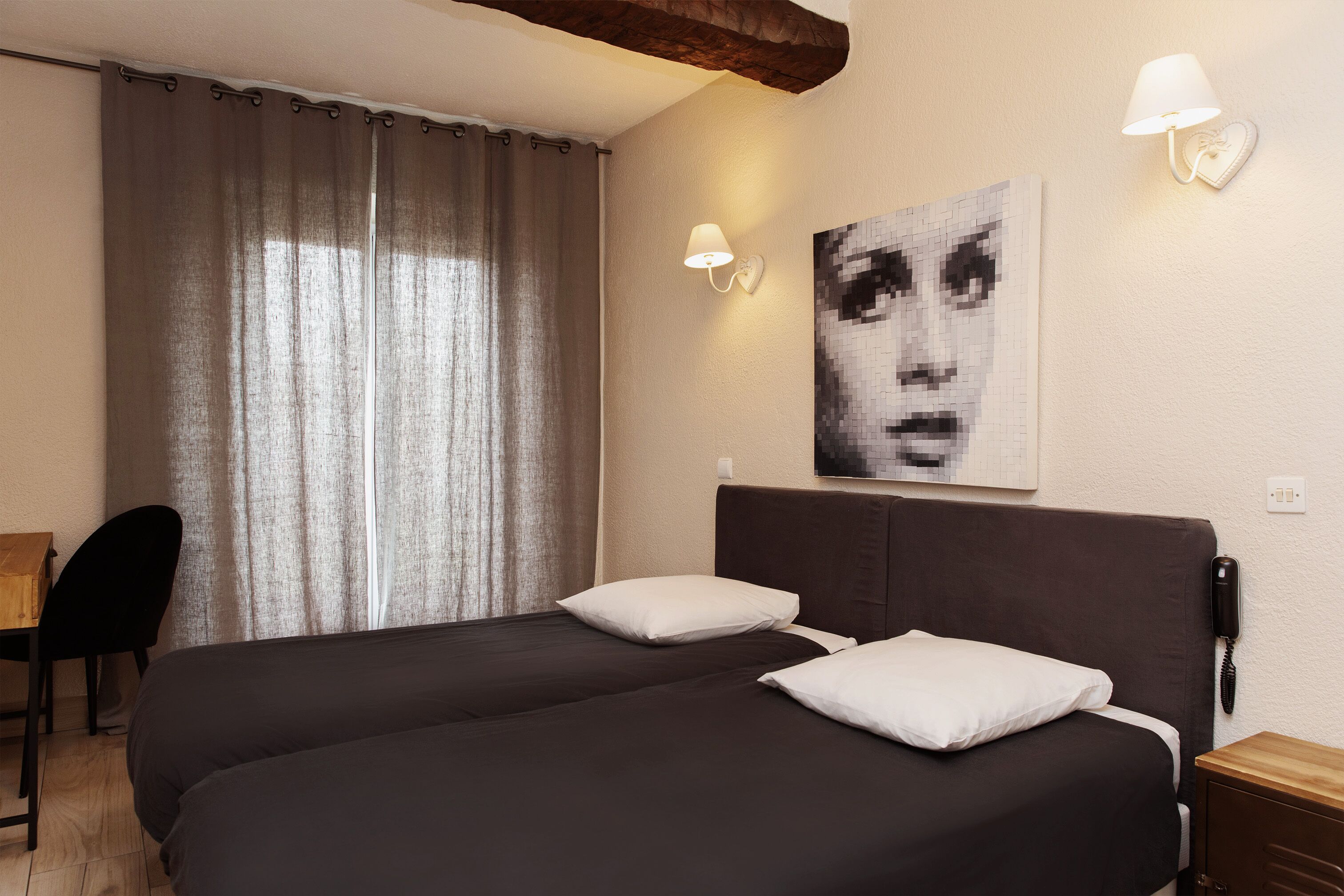Habitación de hotel con una cama grande, dos lámparas de noche, un escritorio, una silla y un teléfono en la pared.
