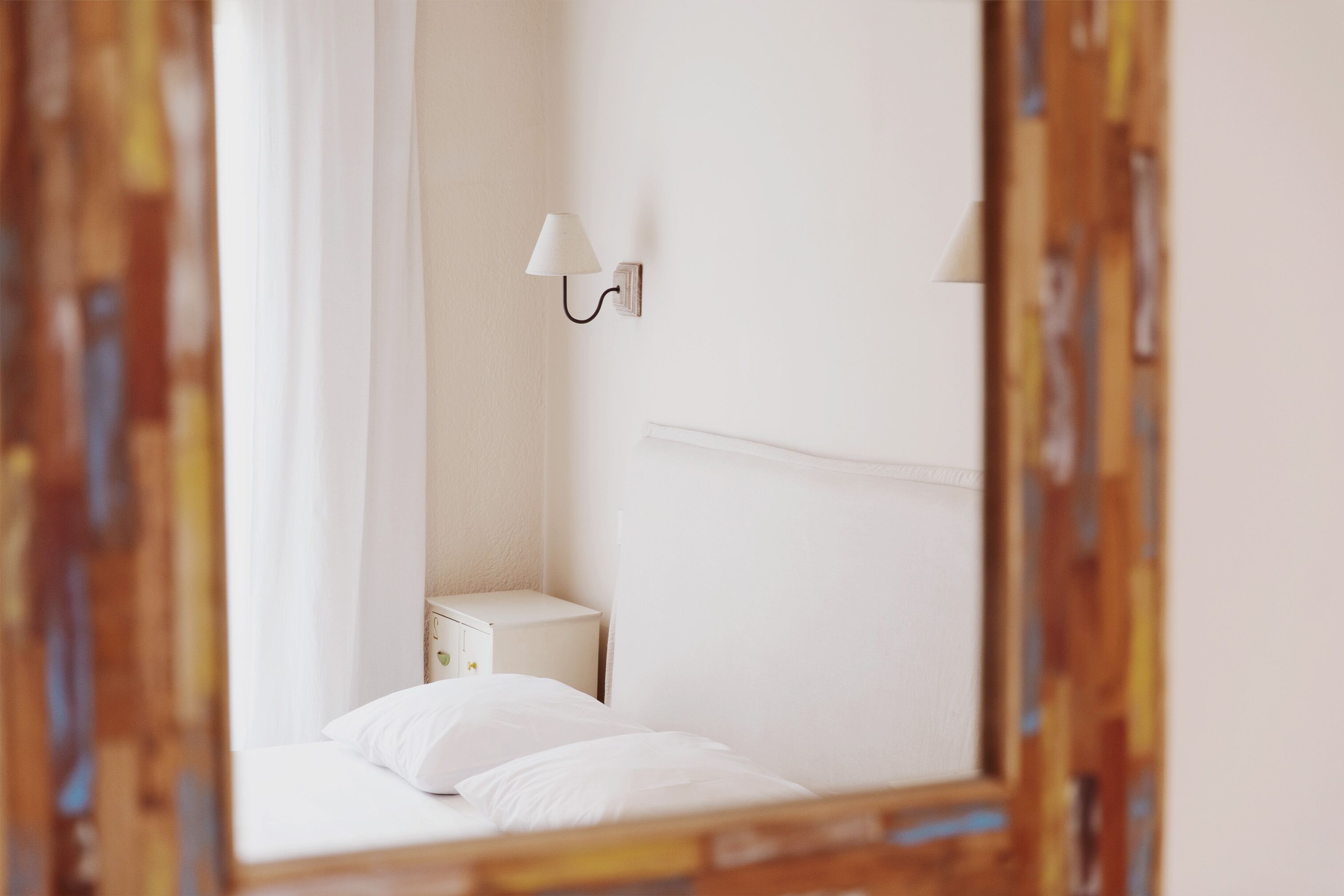 Un dormitorio con cama, mesita de noche y lámpara de pared.