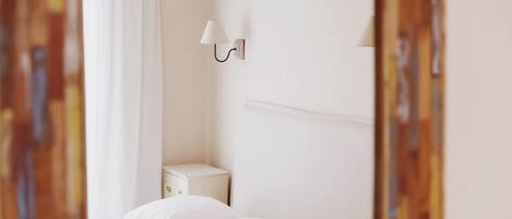 Un dormitorio con cama, mesita de noche y lámpara de pared.