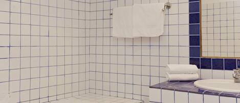 Un baño con azulejos blancos y azules, una bañera blanca y un lavabo con un espejo encima.