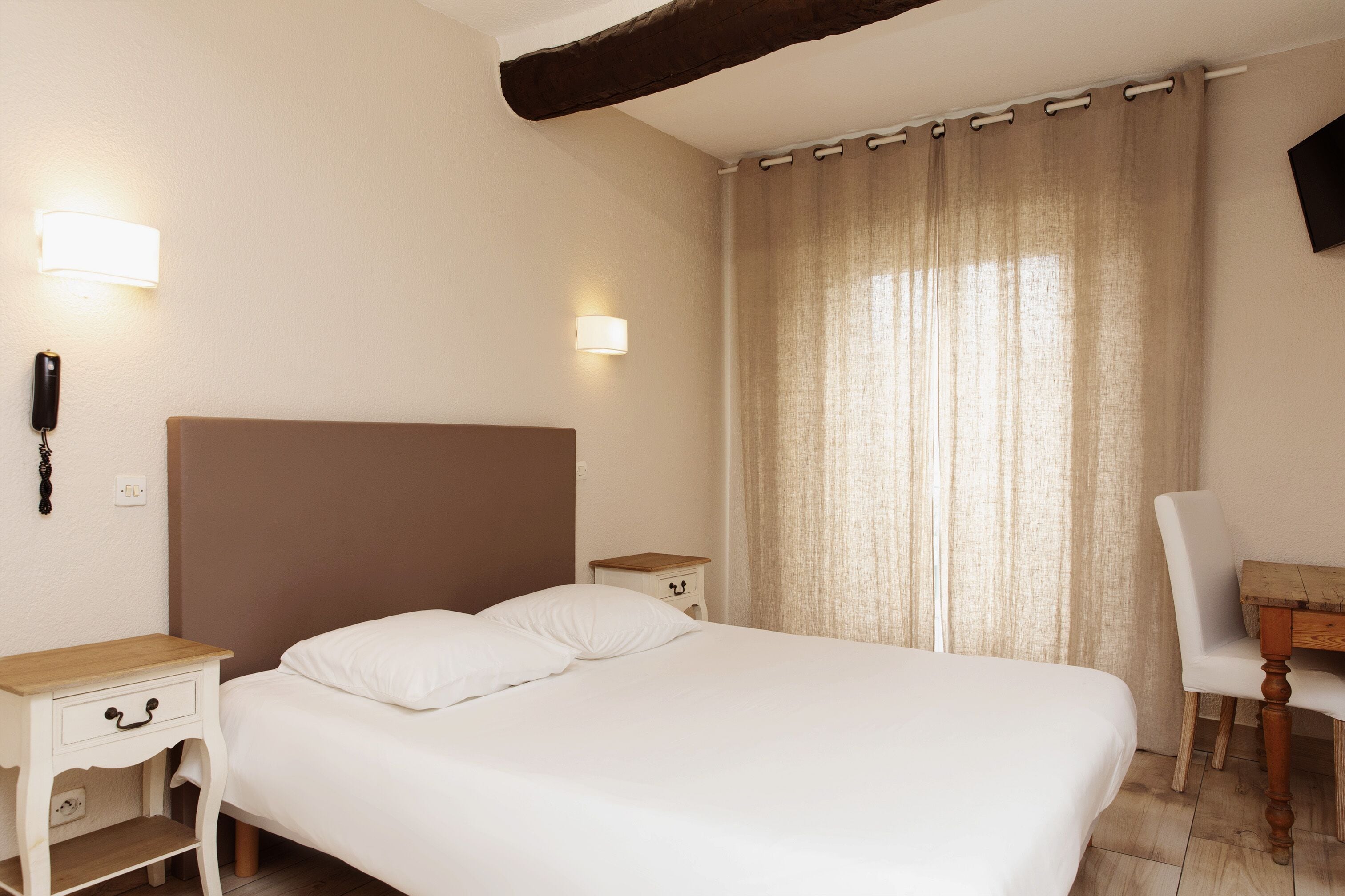 A bedroom with a large bed, bedside tables, a desk, and a chair.