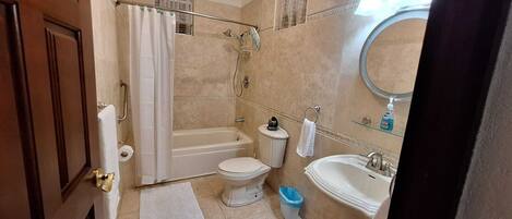 A bathroom with a bathtub, toilet, sink, and shower.