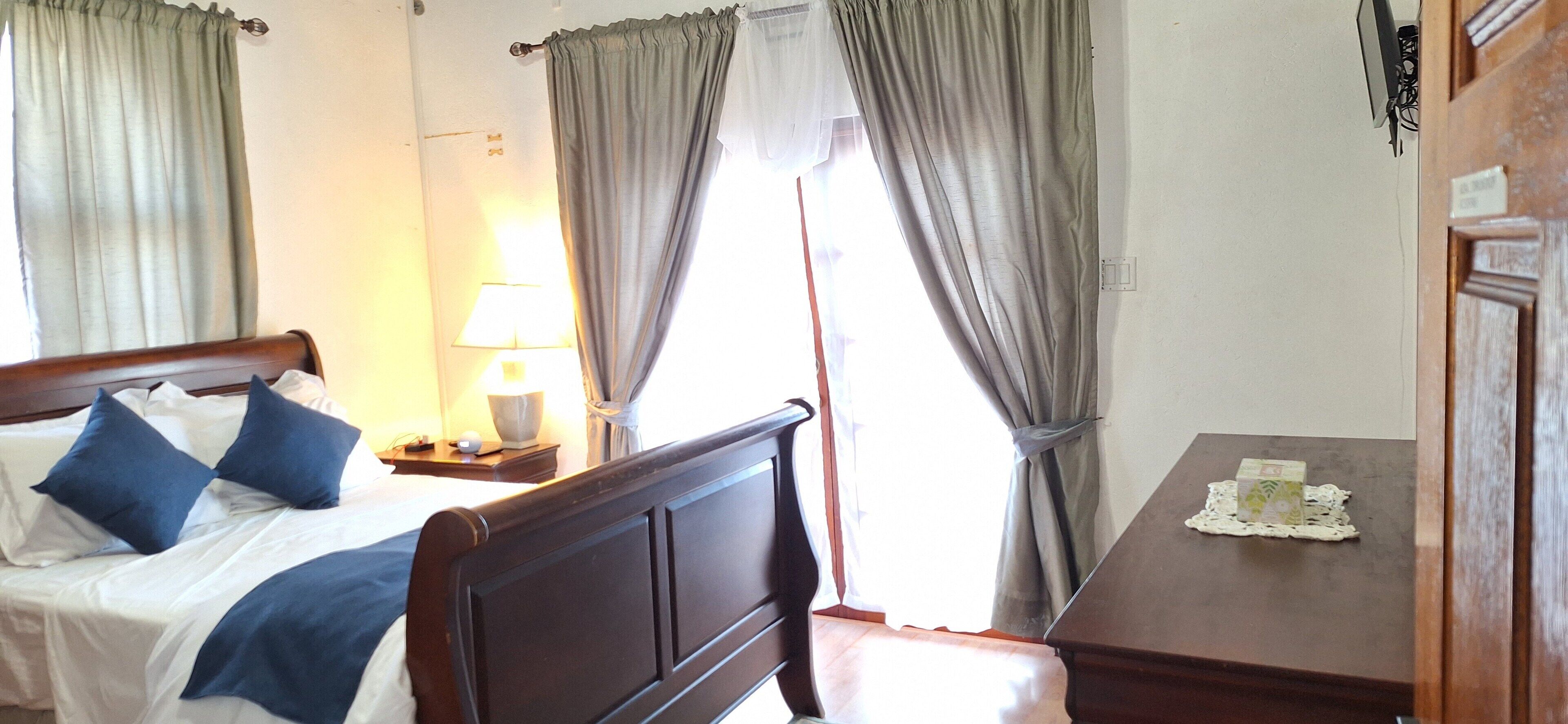 Una habitación de hotel con una cama, una mesita de noche con lámpara y una pequeña mesa con un objeto decorativo.