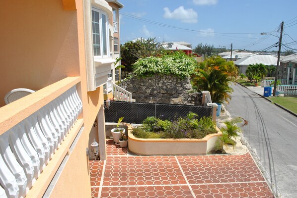 A balcony with a stone wall, potted plants, and a tiled floor.
