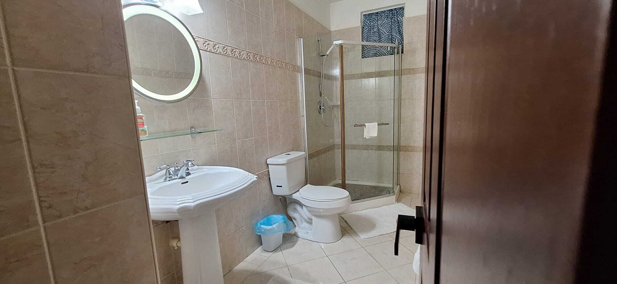 A bathroom with a sink, toilet, and glass-enclosed shower.