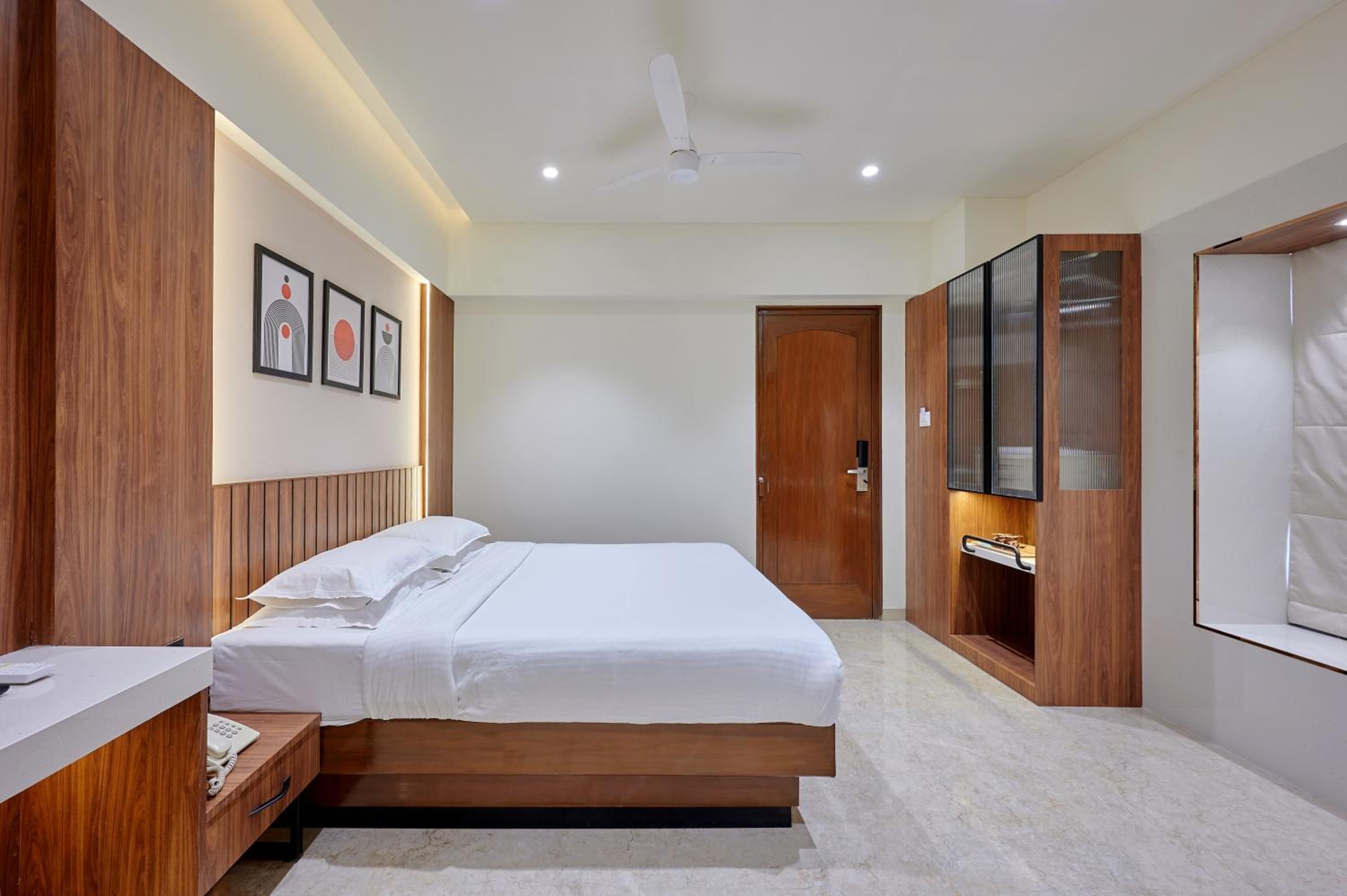 A bedroom with a bed, a bedside table, a wardrobe, a mirror, and a ceiling fan.