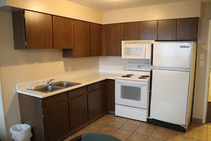 Una cocina con armarios de madera, una estufa blanca, un microondas y un refrigerador.
