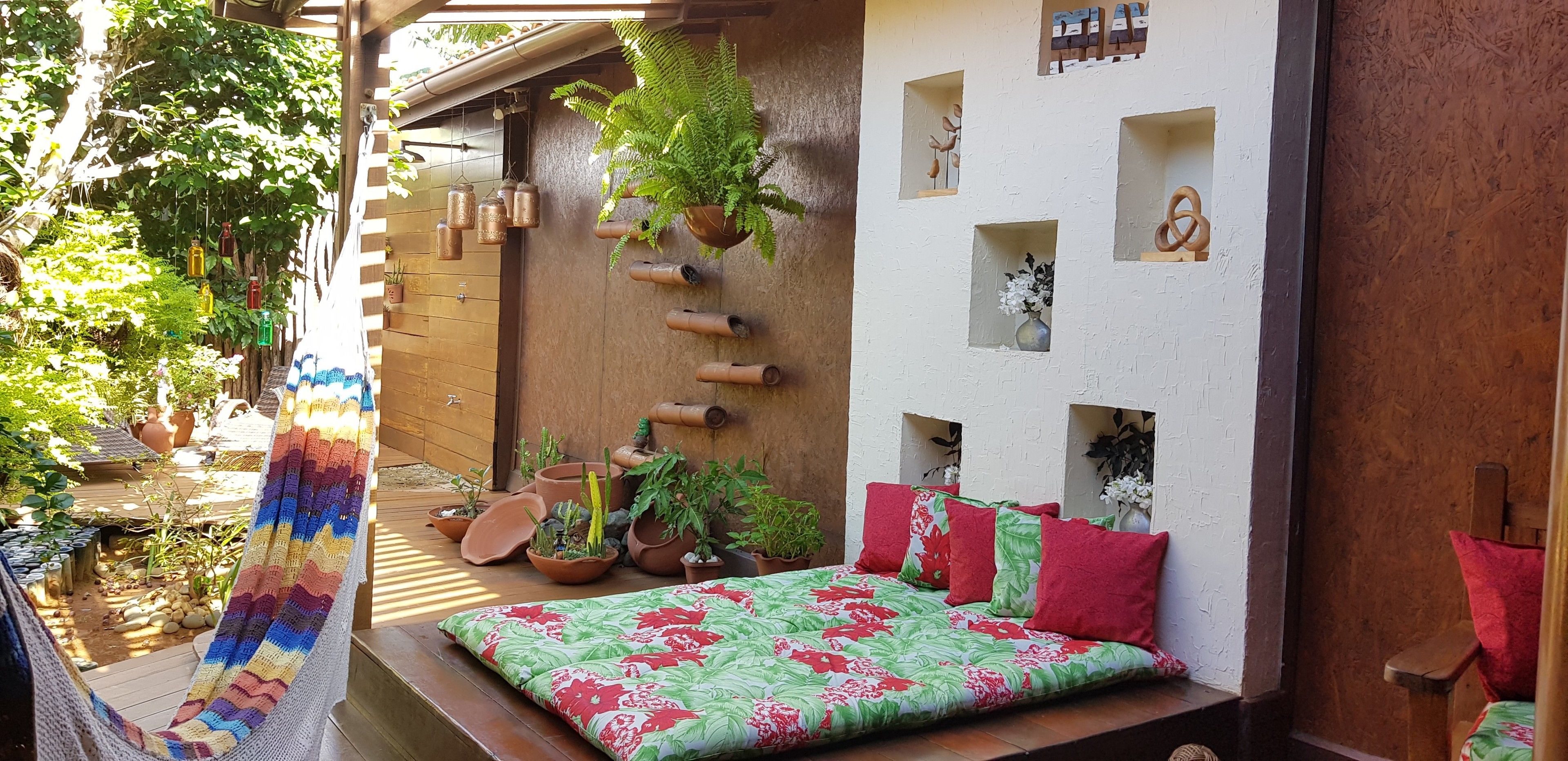 A cozy outdoor seating area with a bed, potted plants, and a hammock.