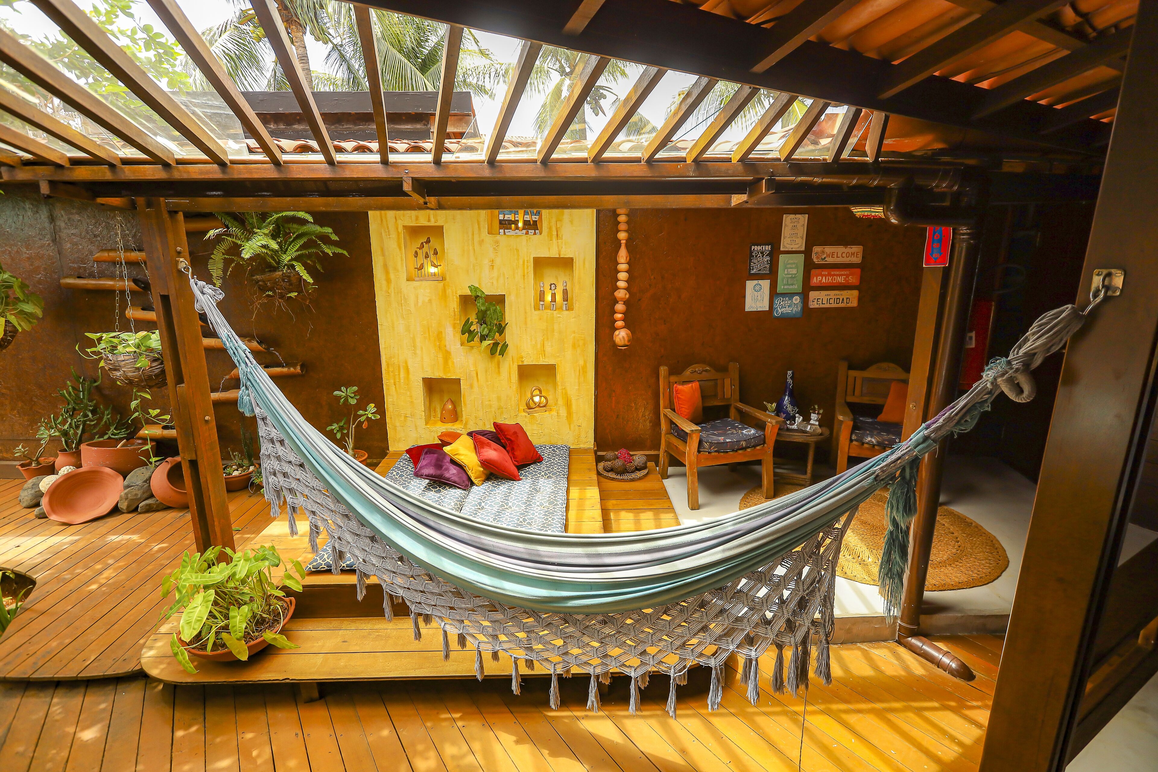 Una hamaca en una habitación de madera con suelo de madera, una mesita pequeña y una silla.