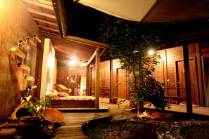 Una habitación tradicional japonesa con suelo de tatami, una mesa baja de madera y un pequeño jardín con un estanque.