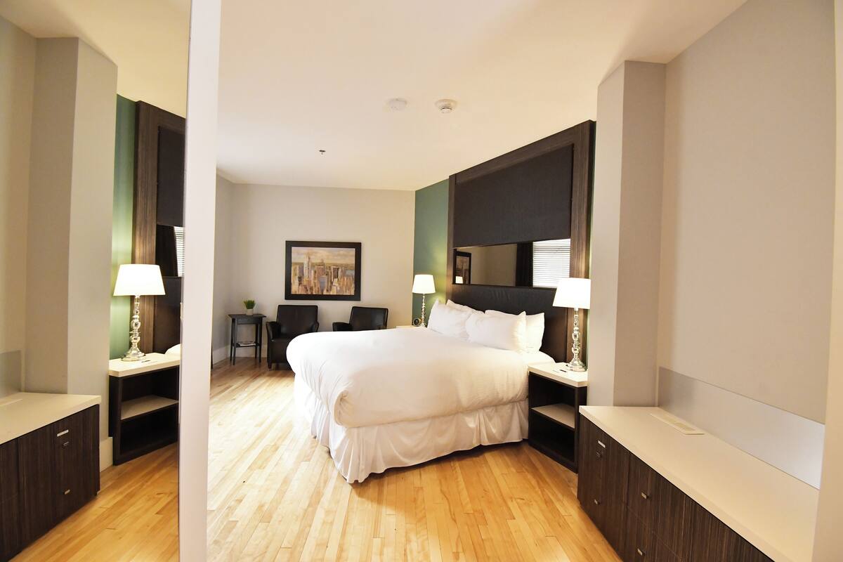 A hotel room with a large bed, bedside tables, a desk, and a chair.