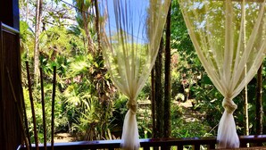 A room with a view of a lush garden through sheer curtains. - Hotel El Encanto (Cahuita)