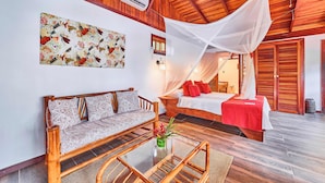 A room with a bed, a sofa, and a glass coffee table. - Hotel El Encanto (Cahuita)