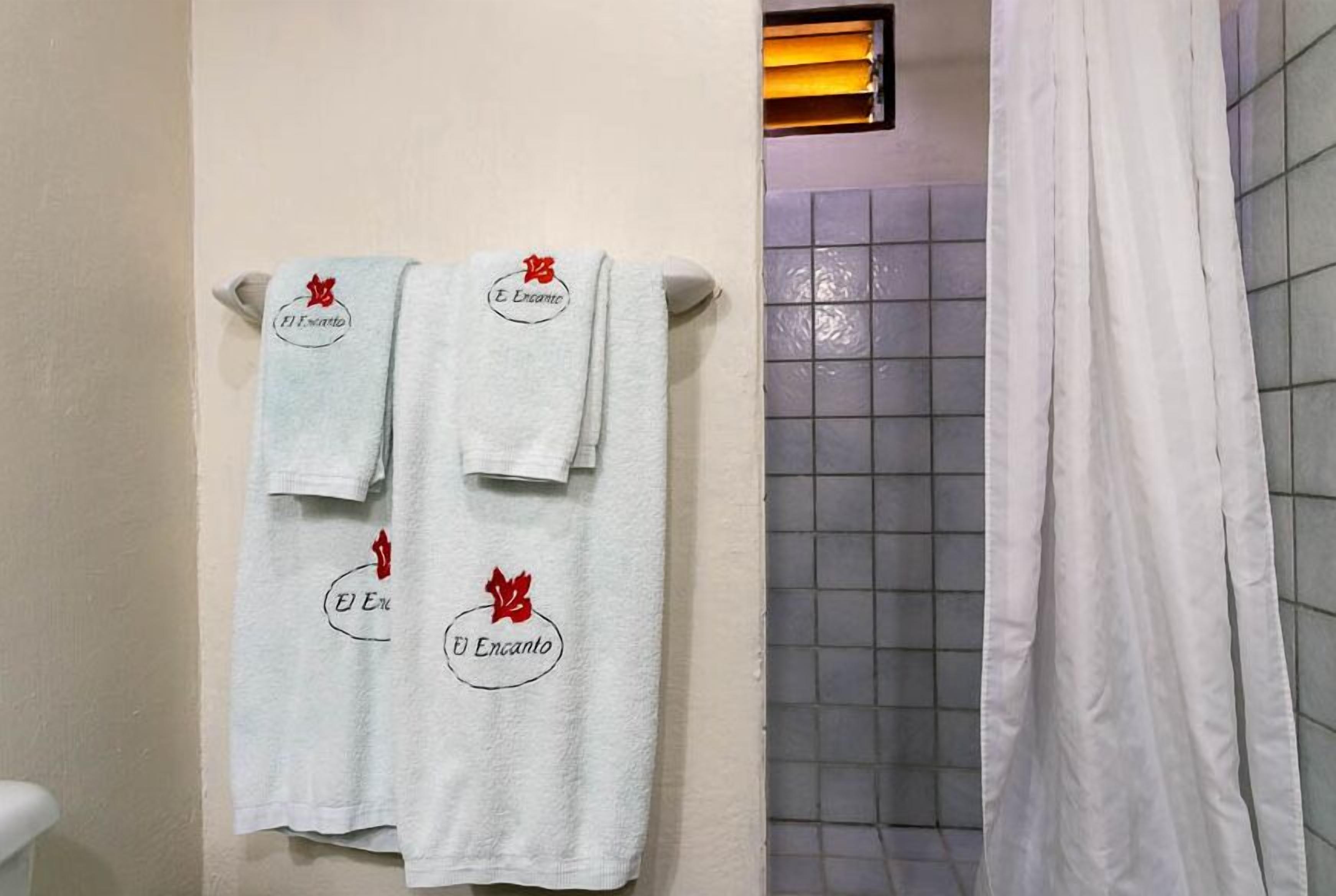 A bathroom with three towels hanging on a rack, each with a logo and text.