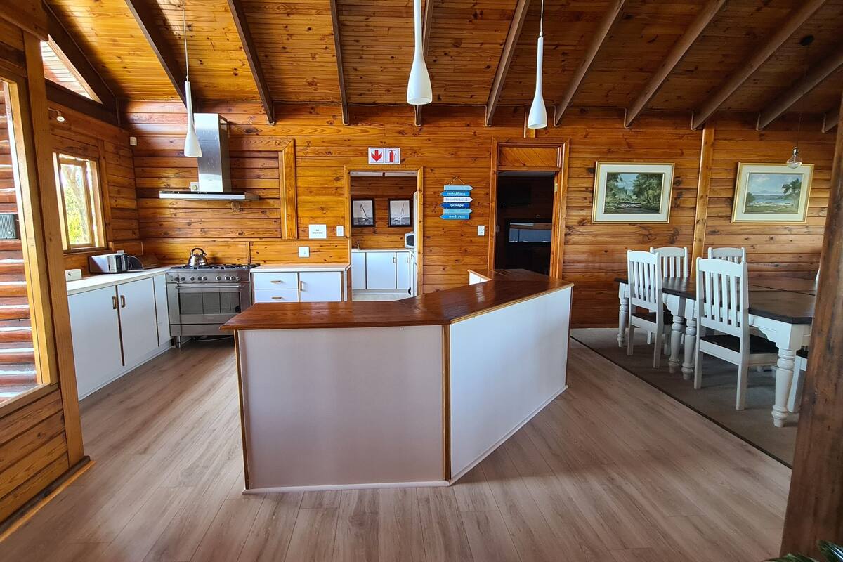 A wooden cabin interior with a kitchen, dining area, and a central island.