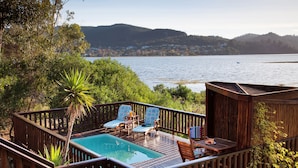 A wooden deck with a pool, two lounge chairs, and a small table.