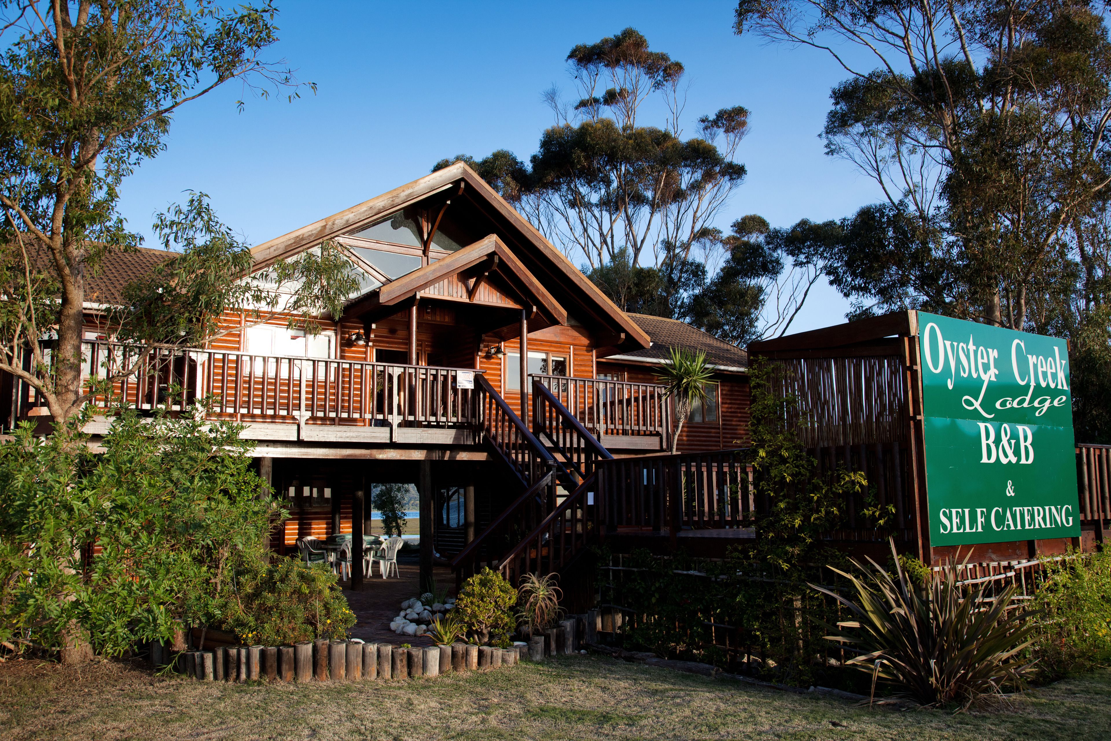 A two-story lodge with a balcony, wooden exterior, and a sign indicating self-catering facilities.