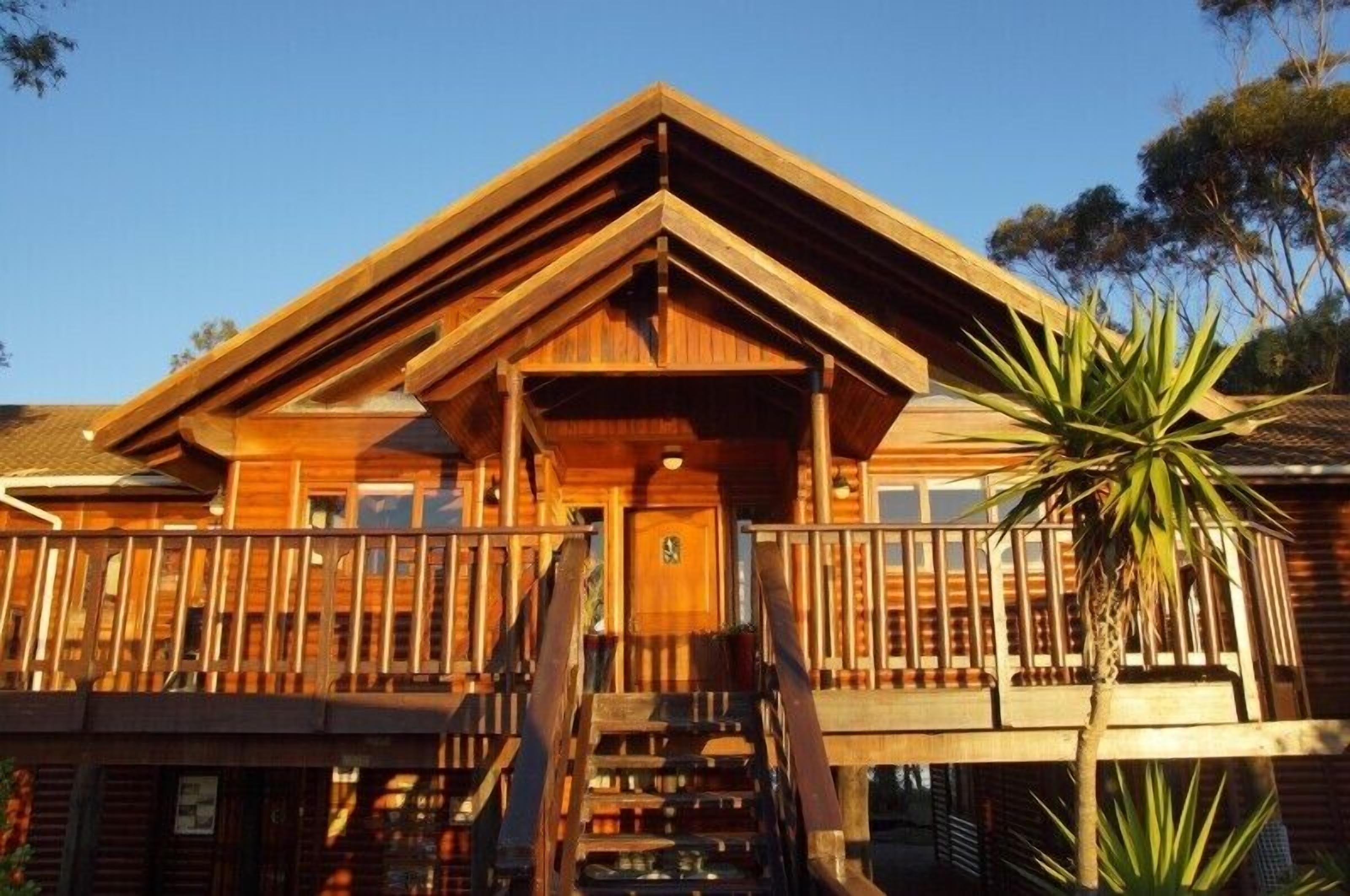 A wooden cabin with a balcony, a staircase, and a door.