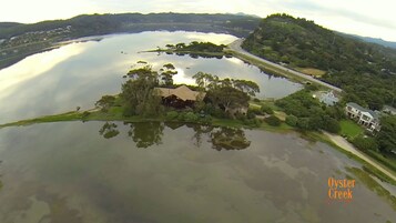 An aerial view of a lake with a house surrounded by trees and a road.