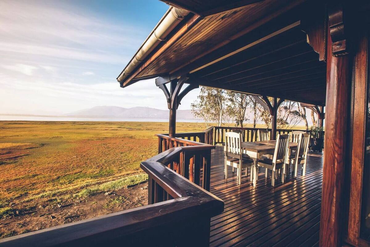A wooden deck with outdoor seating, overlooking a vast landscape with distant mountains.