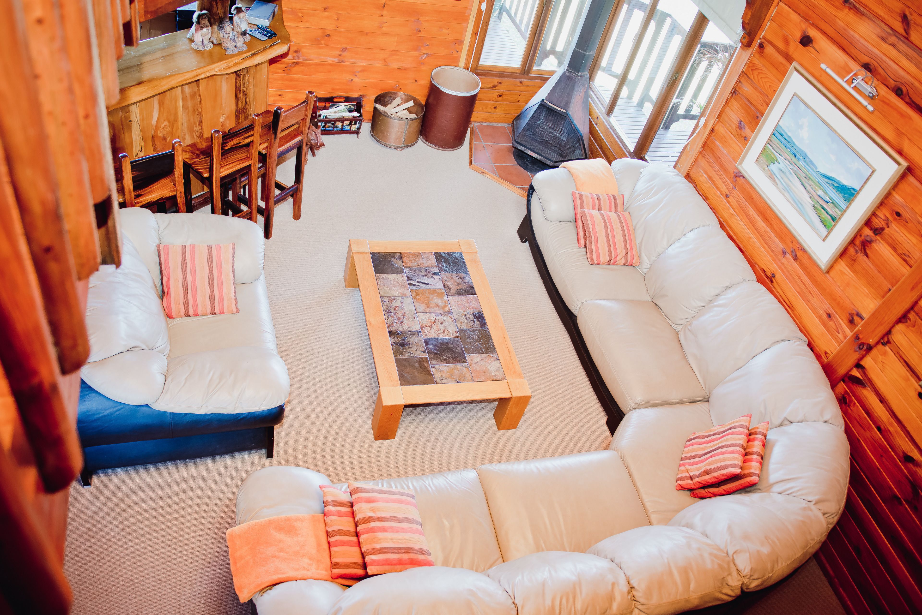 A cozy cabin interior with a wooden interior, a sofa set, a coffee table, and a fireplace.