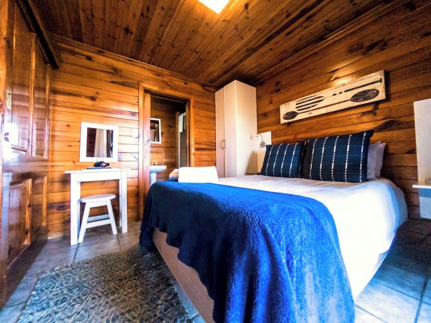 Camera da letto in una baita di legno con un letto, una scrivania e una sedia.