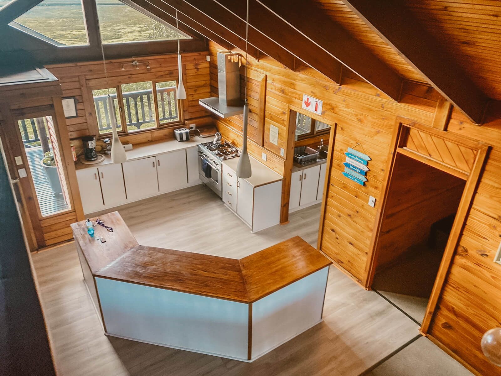 A modern kitchen with wooden walls, a central island, and a view of the outdoors.