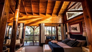 A cozy log cabin bedroom with a large bed, a sofa, and a desk.