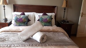 A neatly made bed with a floral-patterned pillow, a rolled-up blanket, and a wooden headboard. - Almara House (Galway)