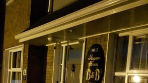Un bâtiment sur lequel est apposée une enseigne indiquant « Almara House B&B, n° 2 » et qui dispose d’un petit espace extérieur aménagé avec un banc.