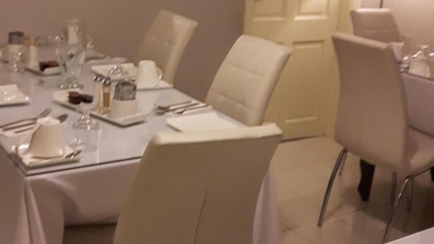 Un espace repas avec une longue table dressée pour le repas, entourée de chaises.