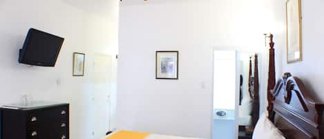 Un dormitorio con cama, ventilador de techo, televisor y cómoda.