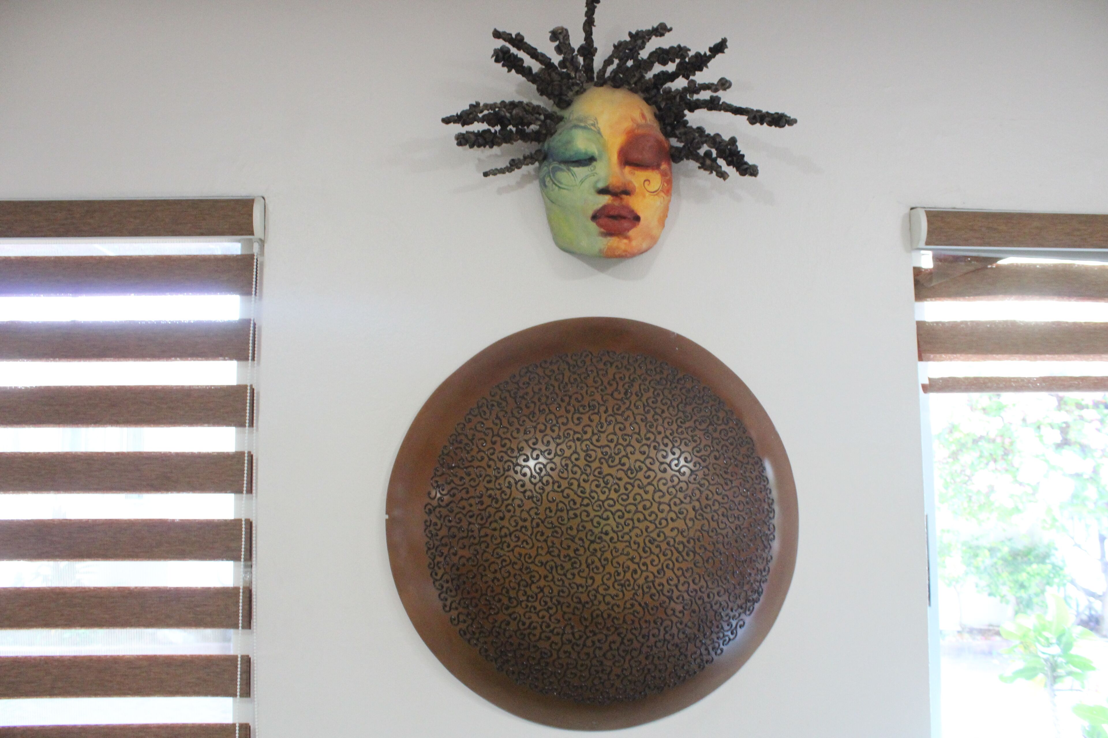 A room with a decorative mask and a textured bowl on the wall.