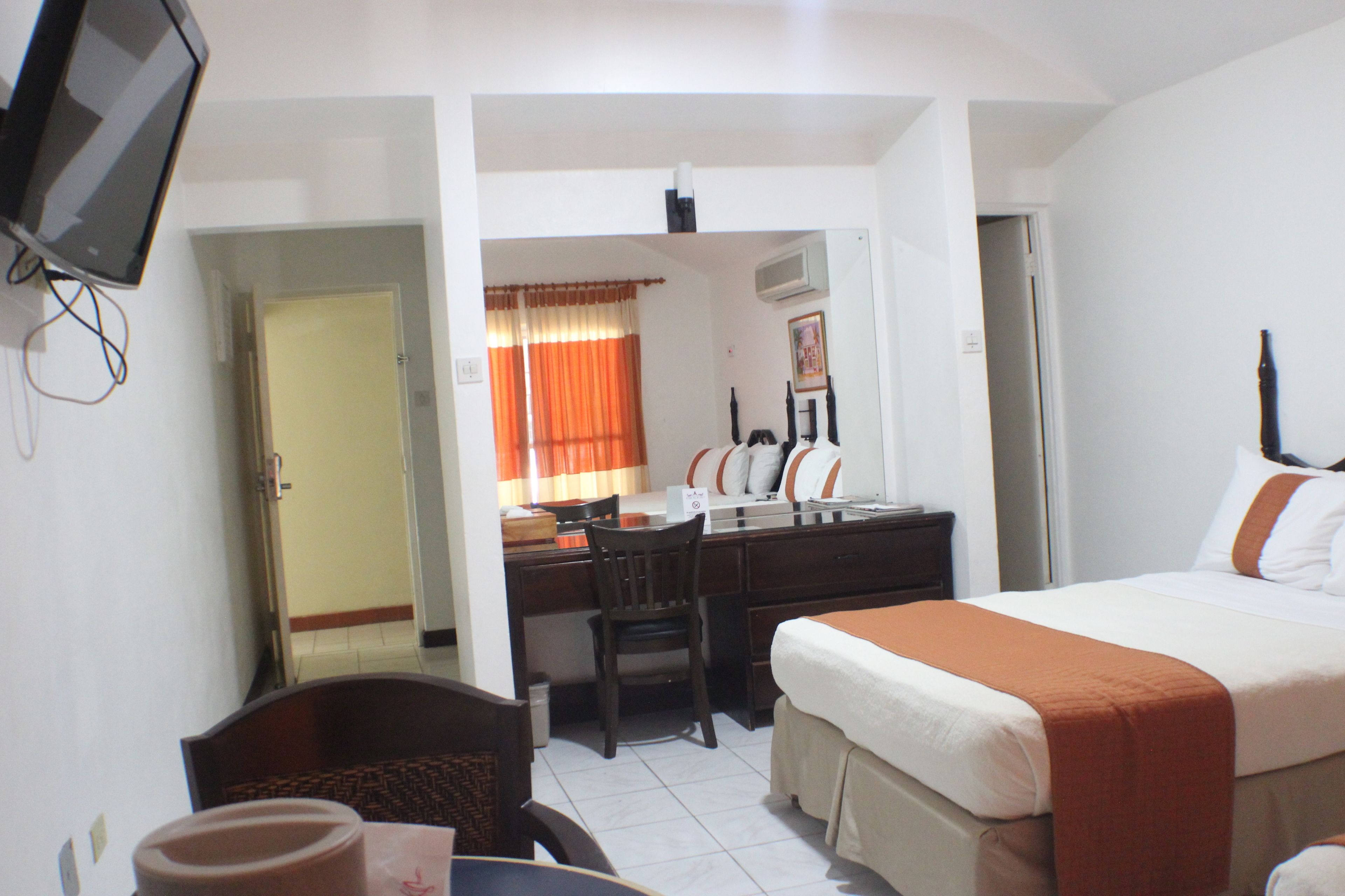 A hotel room with a bed, desk, chair, and a television.