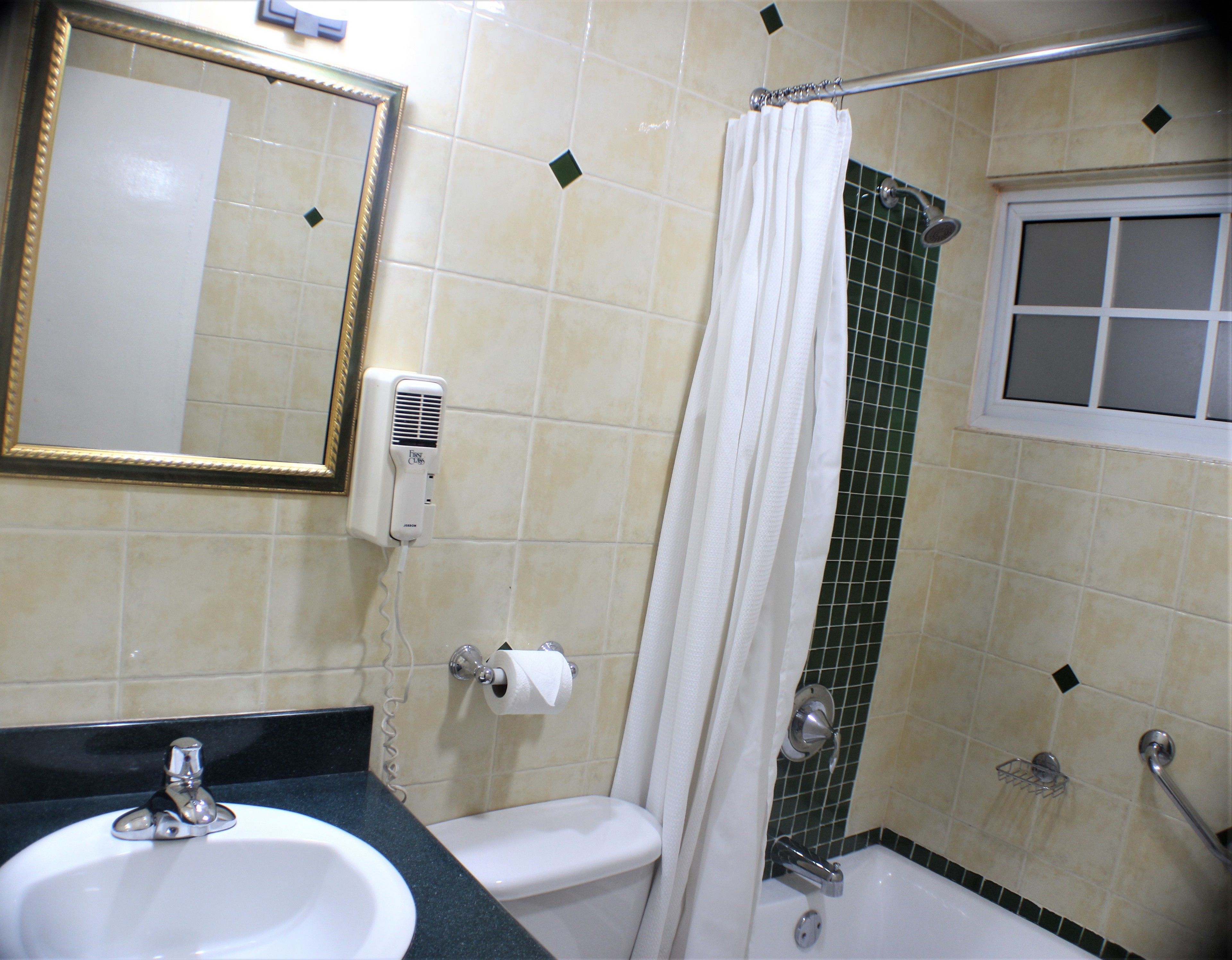 Une salle de bain équipée d’un lavabo, de toilettes, d’une douche et d’un miroir avec un cadre doré.