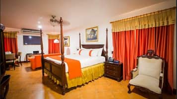A four-poster bed with a wooden frame, a bedside table, a chair, and a desk with a chair.