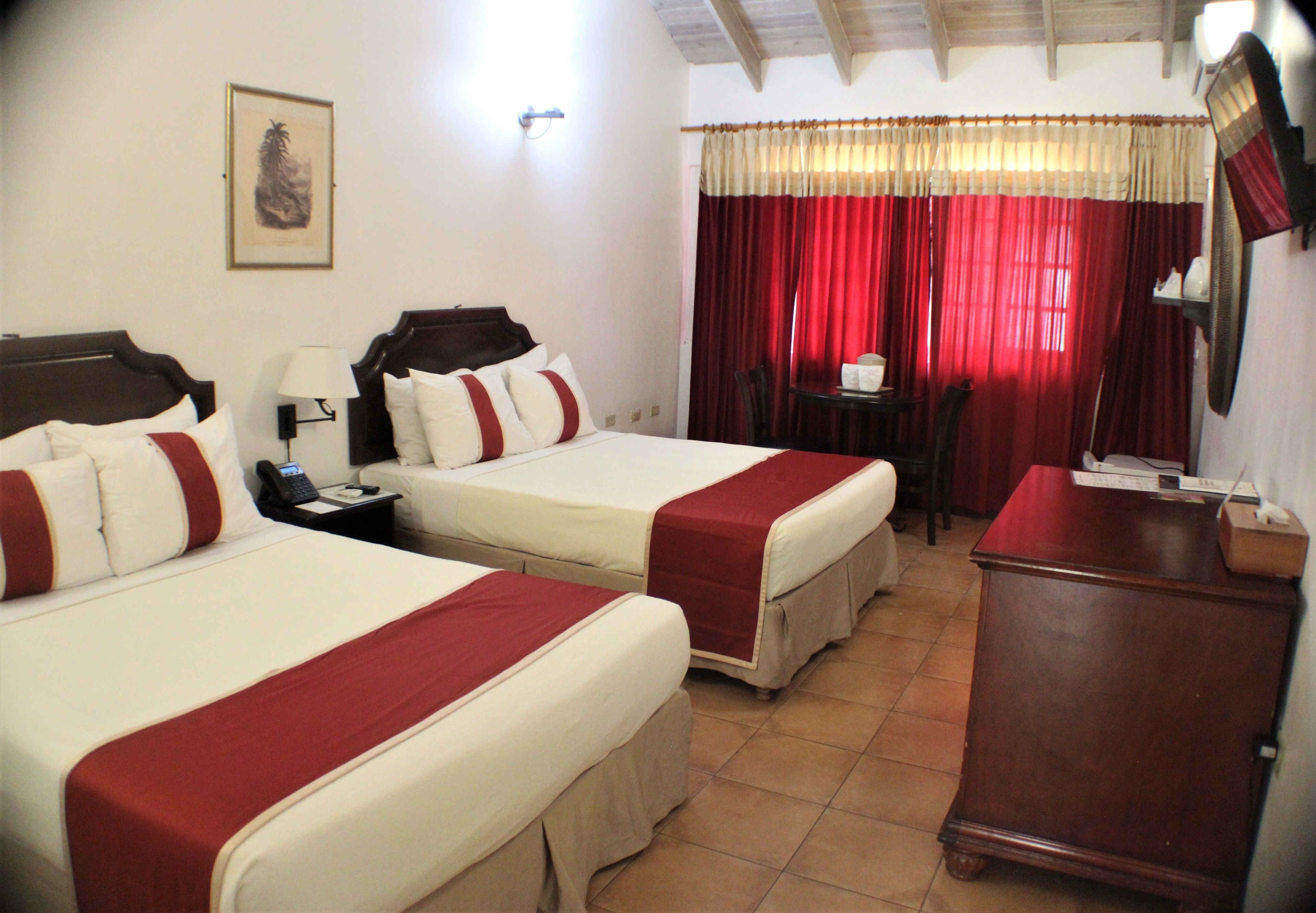 Habitación de hotel con dos camas, un escritorio, una silla y un aparador de madera.