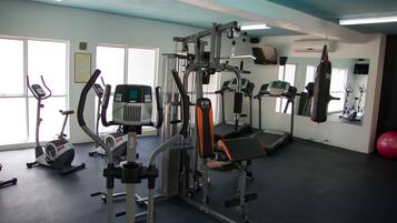 A gym with various exercise equipment, including treadmills, elliptical machines, and weight machines.