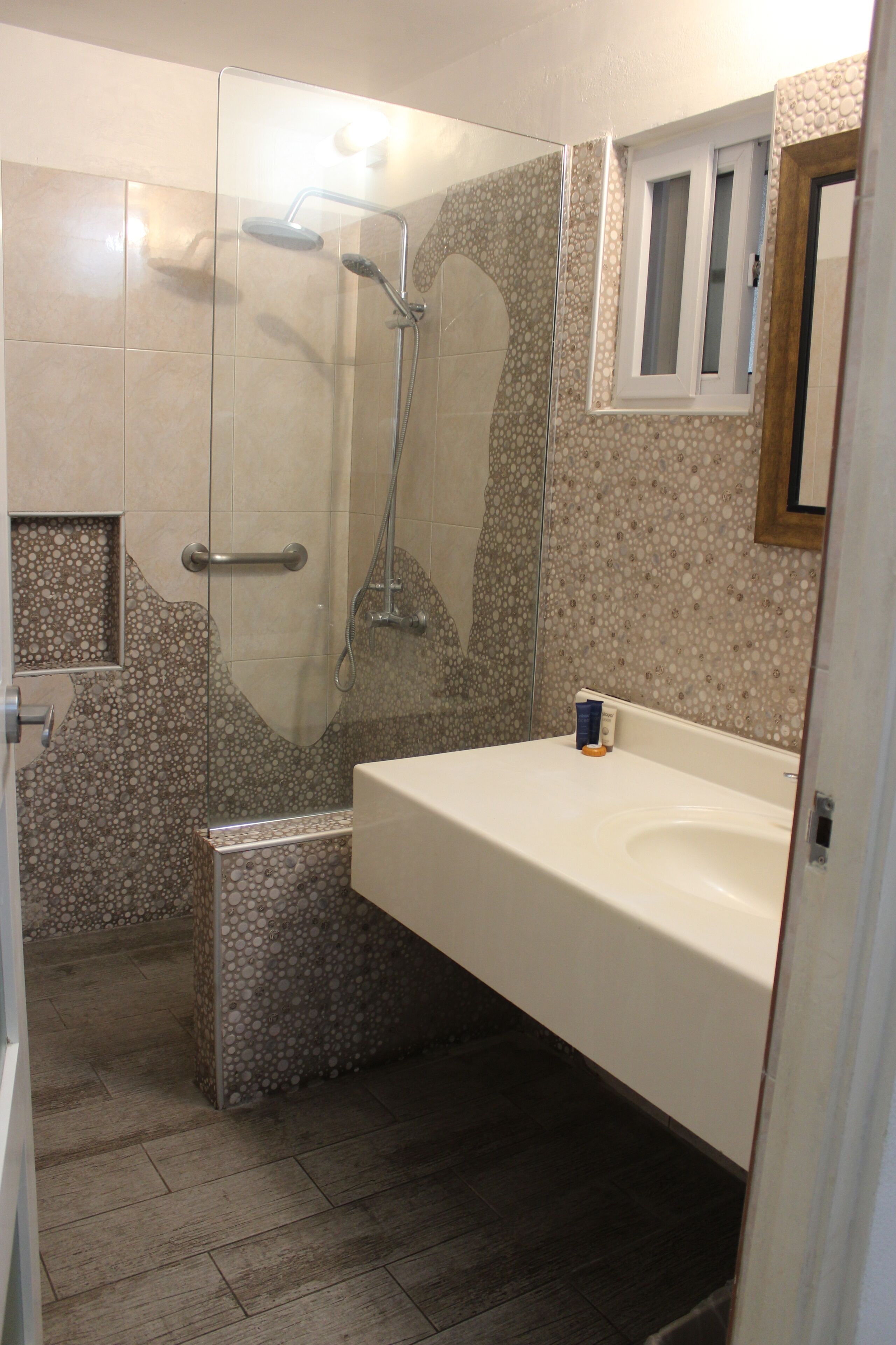 A bathroom with a shower, a sink, and a mirror.