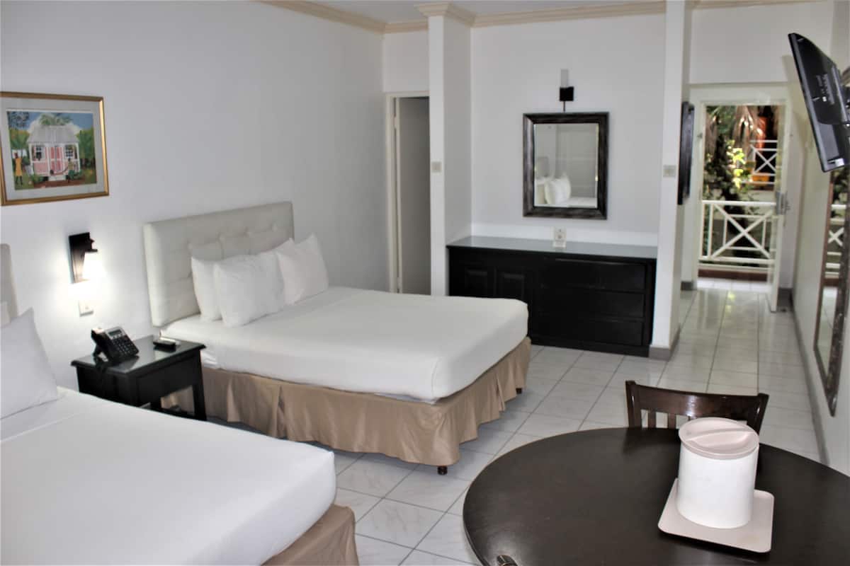 A hotel room with a bed, bedside table, lamp, and a dining table with a chair.
