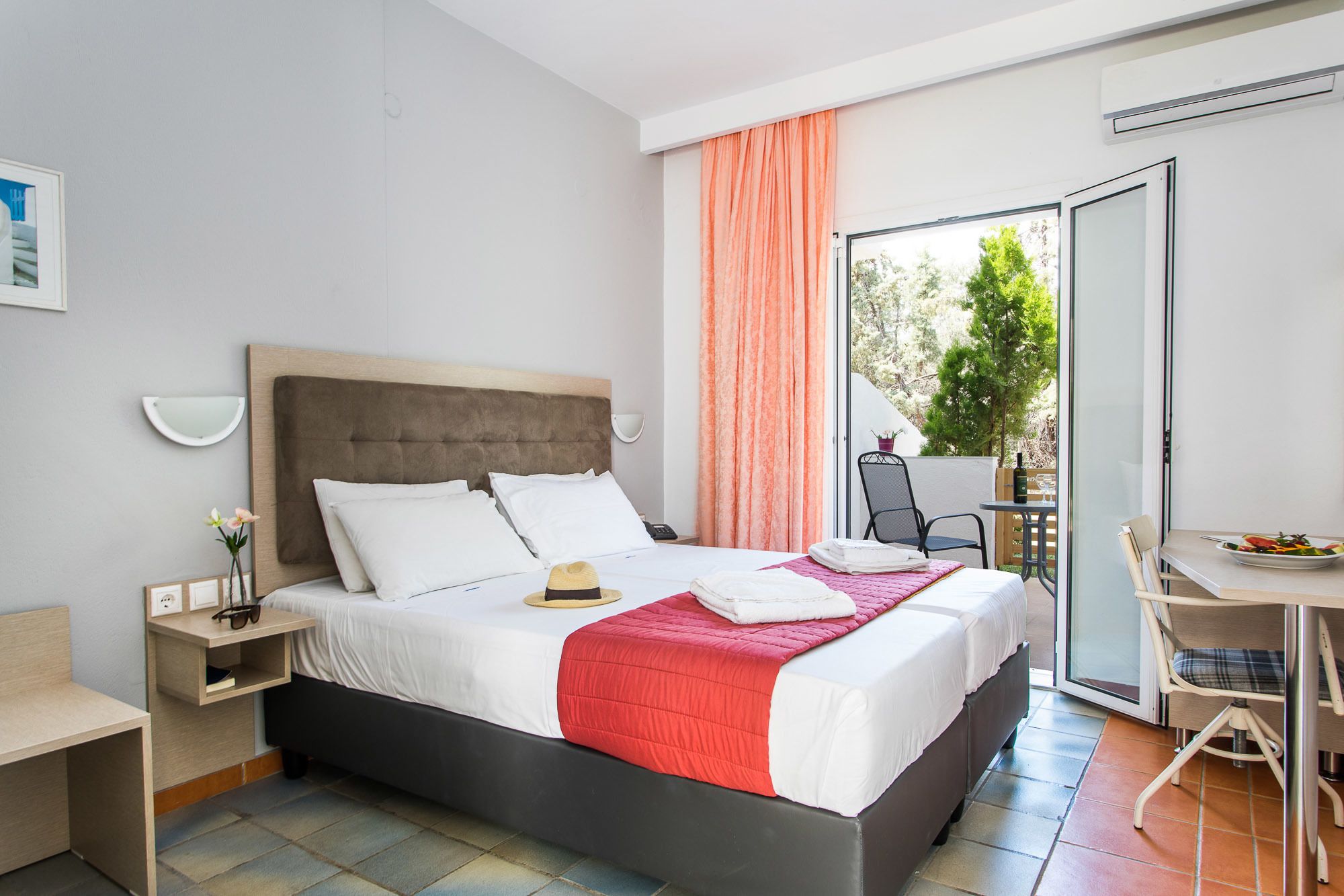 Una habitación de hotel moderna con una cama, un escritorio, una silla y un balcón con mesa y sillas.