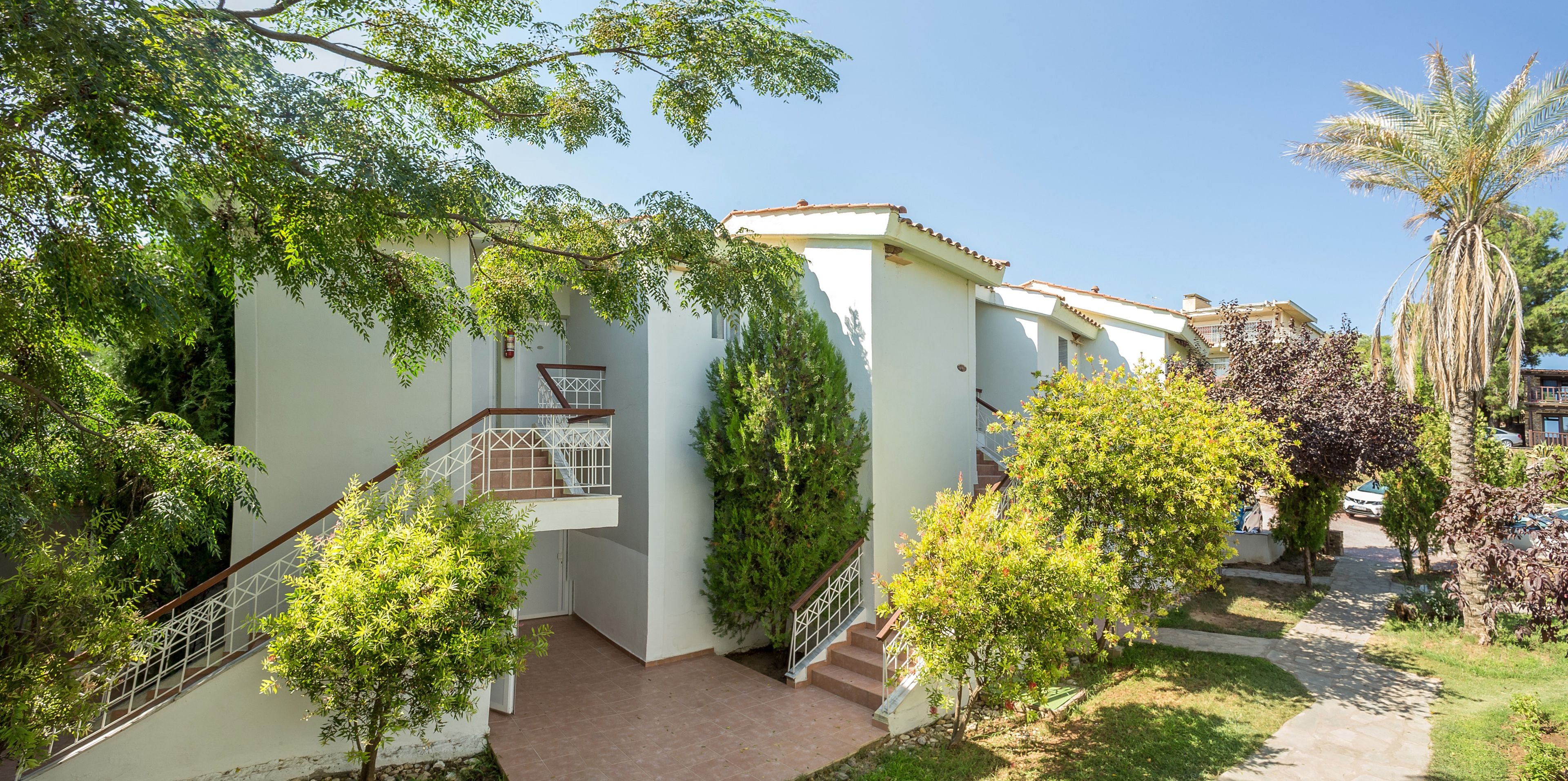 Un edificio residencial con escaleras, un pequeño jardín y una palmera.