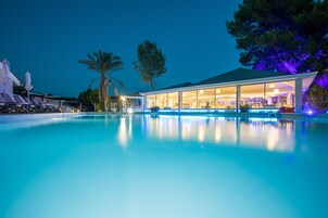 Una piscina al aire libre, sombrillas, sillones reclinables de piscina