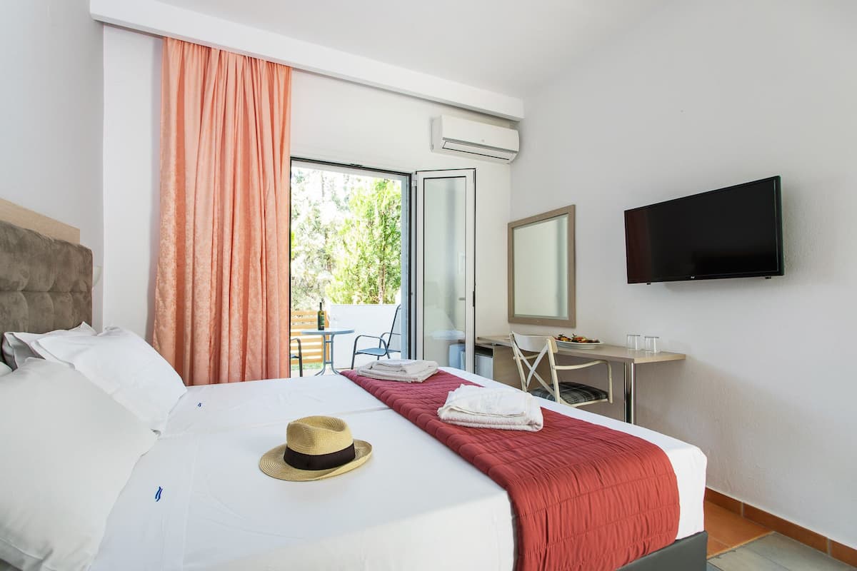 Ein Hotelzimmer mit Bett, Schreibtisch, Stuhl, Fernseher und einem Fenster mit Vorhängen.