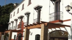 Un edificio con fachada blanca, varias ventanas y un balcón con barandilla.