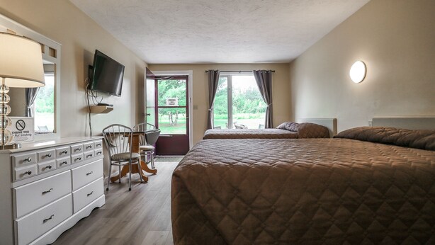 Un dormitorio con una cama grande, televisión montada en la pared, cómoda y una silla.